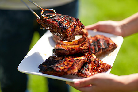 食物,人,吃烹饪的男人着钳子夏天的聚会上把烤肉放盘子里男人夏天的聚会烧烤上饭图片