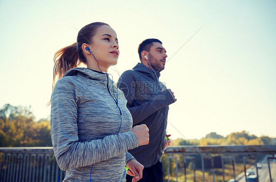 健身,运动,人生活方式的快乐的夫妇与耳机运行户外快乐的夫妇与耳机运行户外图片