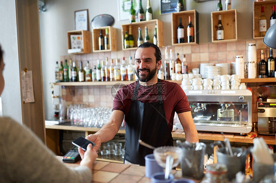 小企业,人服务理念快乐的人服务员围裙与读卡器客户与智能手机支付咖啡厅酒吧酒吧男招待读卡器智能手机的女人图片