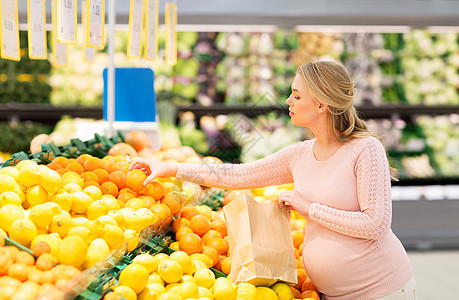 销售,购物,食物,怀孕人们的快乐的孕妇带着纸袋杂货店超市橘子孕妇带着袋子杂货店买橘子图片
