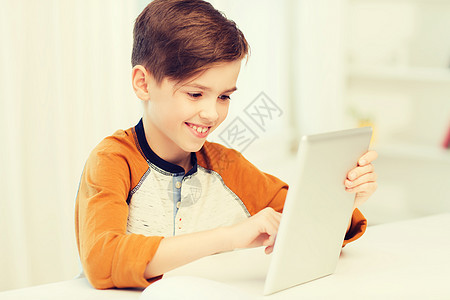 休闲,儿童,技术人的微笑男孩与平板电脑家里微笑的男孩家里用平板电脑电脑图片