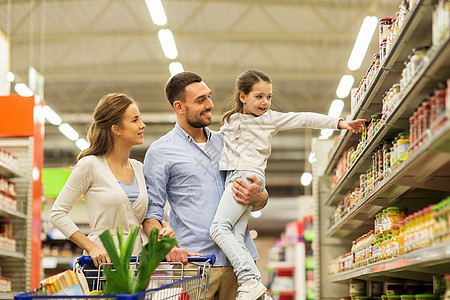 销售,消费主义人们的幸福的家庭与孩子购物车购买食品杂货店超市杂货店购物车里食物的家庭图片