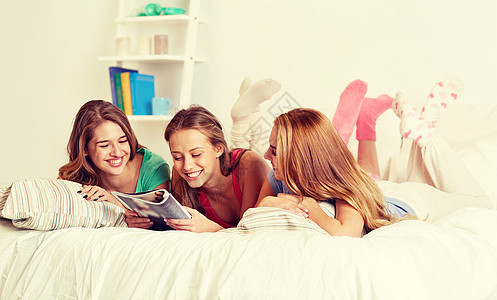 友谊,人睡衣派的快乐的朋友十几岁的女孩家里床上阅读杂志朋友十几岁的女孩家看杂志图片