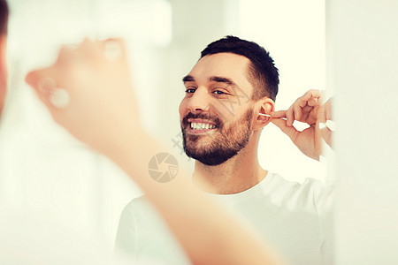 美丽,卫生人的微笑的轻人用棉签清洁耳朵,家里的浴室看镜子男人浴室用棉签清洁耳朵图片