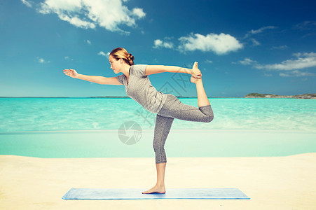 健身,运动,人健康的生活方式妇女瑜伽的主舞姿势垫子上的海洋天空背景女人瑜伽的主舞姿势图片