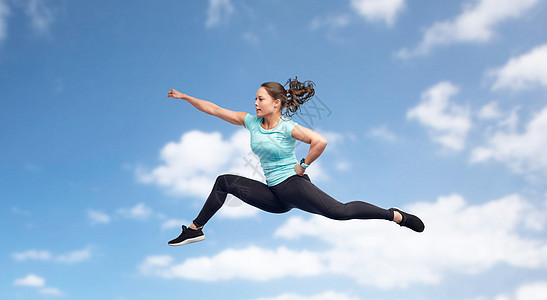 运动,健身,运动人的快乐的轻女人空中跳跃,蓝天背景下的战斗姿势快乐运动的轻女人跳战斗姿势图片