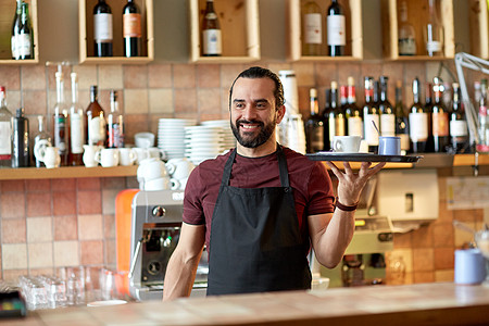 小企业,人服务理念快乐的男人服务员围裙托盘与咖啡杯糖碗酒吧酒吧里咖啡糖的快乐男人侍者图片