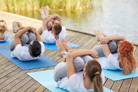 健身,运动,瑜伽健康的生活方式群人膝盖按压姿势河流湖泊泊位群人户外瑜伽练图片
