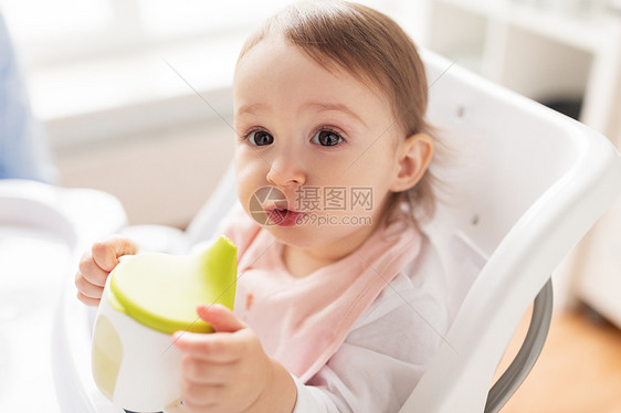 童人们的小婴儿喝喷口杯坐高椅子家里婴儿家里的高椅子上喷口杯里喝水图片