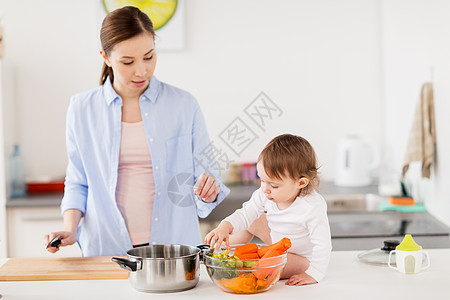 家庭,食物,健康饮食,烹饪人的快乐的母亲小女婴与蔬菜锅家里厨房快乐的母亲婴儿家厨房饭图片