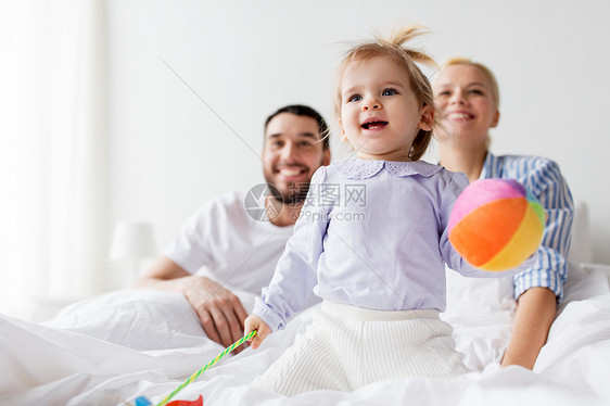 人,家庭早晨的快乐的孩子与玩具父母床上家快乐的孩子带着玩具父母家里睡觉图片