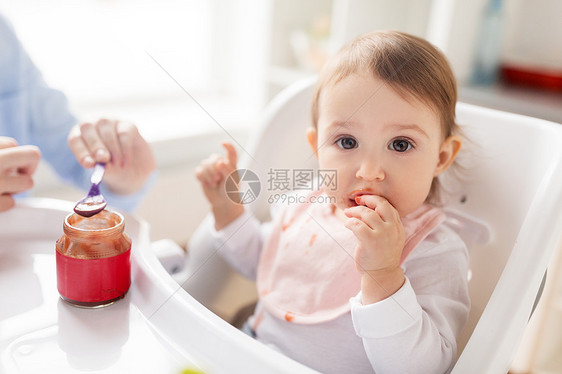 家庭,食物,饮食人的母亲与纯净物勺子喂养小婴儿坐高椅子家里母亲家用泥喂婴儿图片