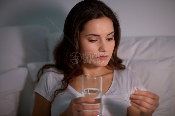 药物,医疗保健人们的妇女晚上的家里床上吃药喝水家里床上药丸水的女人图片