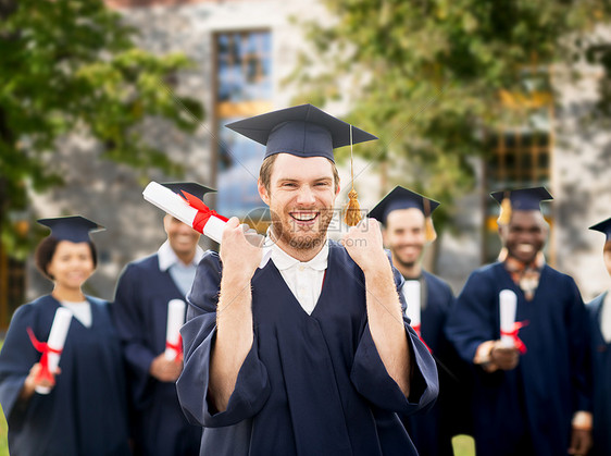 教育手势人的群快乐的国际学生穿着灰浆板学士学位礼服,校园建筑背景下庆祝成功毕业带着文凭庆祝毕业的快乐学生图片