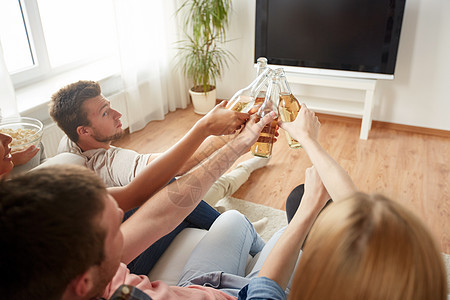 友谊,饮料,酒精,假期人们的快乐的朋友家里碰啤酒瓶看电视朋友们家里碰啤酒看电视图片