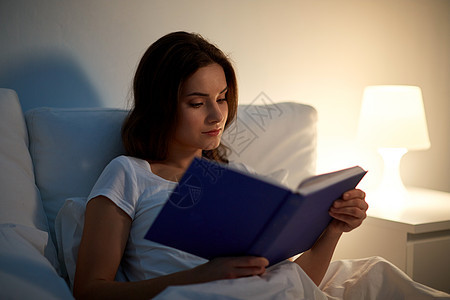休闲人的轻的女人晚上家床上看书轻的女人晚上家床上看书图片