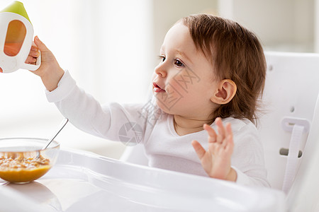 童人们的小婴儿喝喷口杯坐高椅子家里婴儿家里的高椅子上喷口杯里喝水图片