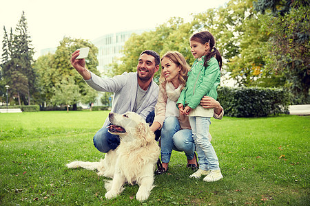 家庭,宠物,动物,技术人的快乐的家庭与拉布拉多猎犬公园用智能手机自拍快乐的家庭与狗自拍智能手机图片
