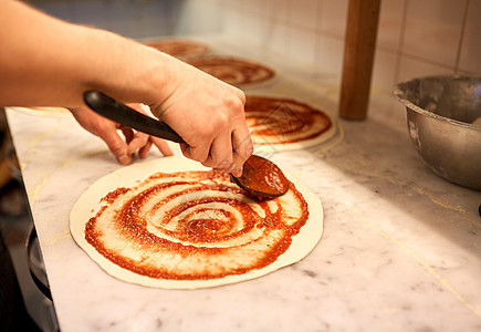 食物,烹饪,意大利菜,人烹饪用勺子烹饪,用番茄酱比萨饼店的生皮萨披萨店用番茄酱披萨图片