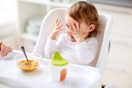 食物,孩子,喂养人的婴儿与勺子坐高椅吃泥家里的厨房婴儿坐高椅子上家吃饭图片