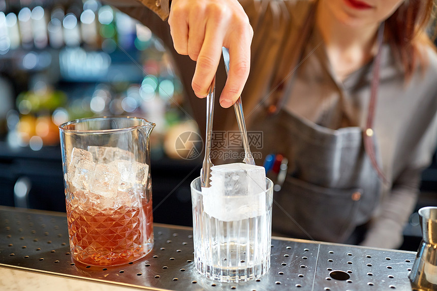 酒精饮料,人豪华女人调酒师与钳子添加冰块璃准备鸡尾酒酒吧柜台酒保酒吧的璃里加入冰块图片