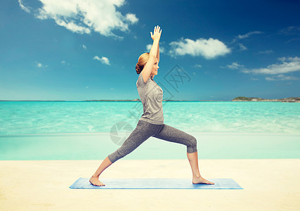 健身,运动,人健康的生活方式妇女瑜伽战士姿势垫子上的海滩背景女人垫子上瑜伽战士的姿势图片