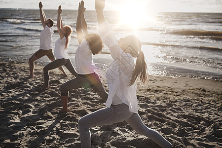 健身,运动,瑜伽健康的生活方式群人海滩上高弓步新月姿势群人海滩上瑜伽练图片