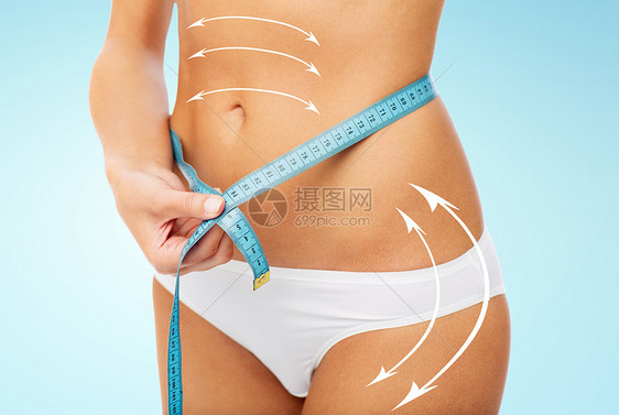 饮食,减肥人的密切妇女的身体与测量磁带围绕腰部蓝色背景用腰部的测量带女身体图片