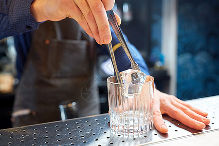 酒精饮料,人豪华酒吧服务员与钳子添加冰块璃准备鸡尾酒酒吧柜台酒保酒吧的璃里加入冰块图片