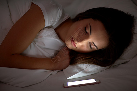 技术人的轻的女人,智能手机,晚上睡家里的床上智能手机的女人晚上睡床上图片