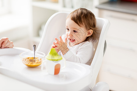 快乐的小女婴坐高椅子上吃饭图片