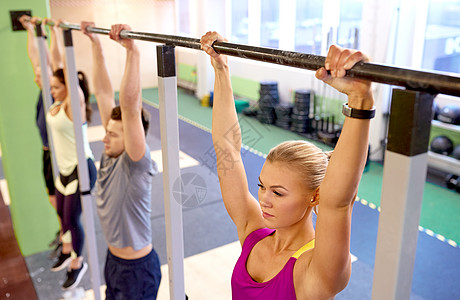 运动,健身,锻炼人的妇女与心率跟踪挂水平杆体训练健身房群人挂健身房的横杆上图片