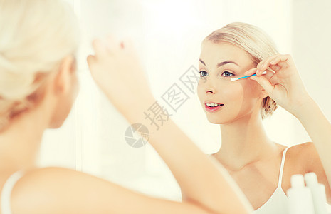 美丽,卫生人的微笑的轻女人用棉签化妆,家里的浴室看镜子女人浴室用棉签化妆图片