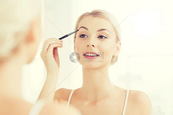 美容,化妆,化妆品,早晨人的轻的女人用刷子画眉,家里的浴室照镜子女人浴室刷眉妆图片