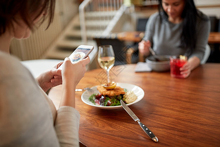 食物,新的北欧美食,技术人的妇女与智能手机包鱼片与酒石酱烤箱烤甜菜根番茄沙拉餐厅晚餐餐馆智能手机食物的图片