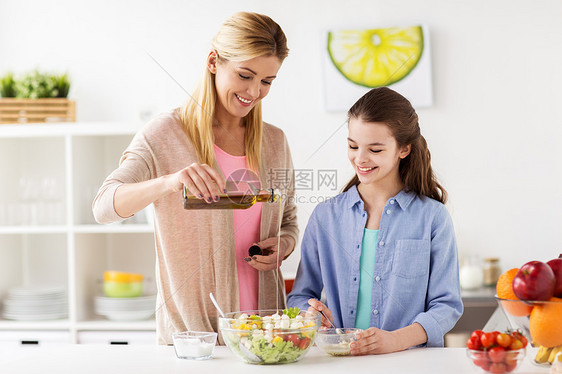 食物,健康饮食,家庭人的快乐的母亲女儿烹饪添加橄榄油蔬菜沙拉家庭厨房晚餐快乐的家庭烹饪沙拉家厨房快乐的家图片