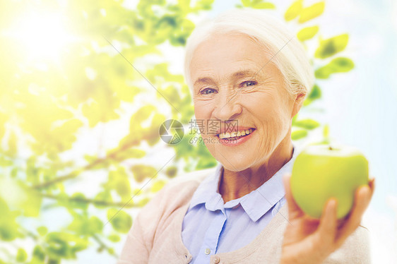 户外手拿青苹果的老年妇女图片