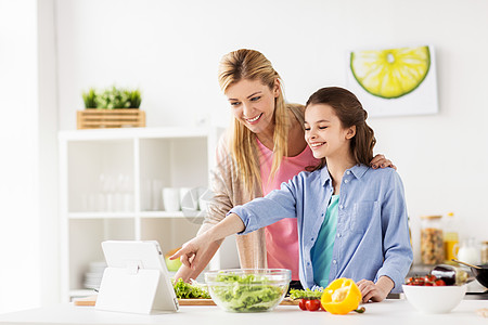 健康饮食,家庭人的快乐的母亲女儿烹饪蔬菜晚餐用线食谱平板电脑电脑家庭厨房家庭烹饪晚餐用平板电脑厨房家图片