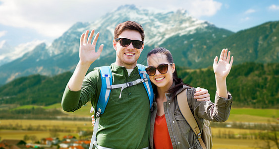 旅行,徒步旅行,背包旅行,旅游人们的幸福的夫妇与背包挥动手阿尔卑斯山的背景快乐的夫妇背包高地旅行快乐的夫妇图片
