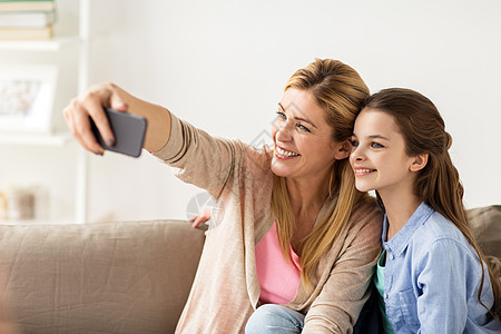 家庭,技术人的快乐的母亲女儿家里用智能手机自拍幸福的家庭家里用智能手机自拍幸福的家庭家里用智能手机自拍图片