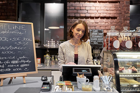 小企业,人服务理念快乐的女人酒吧服务员柜台与现金箱工作咖啡馆咖啡店咖啡馆里带着现金箱的快乐女人酒吧服务员图片
