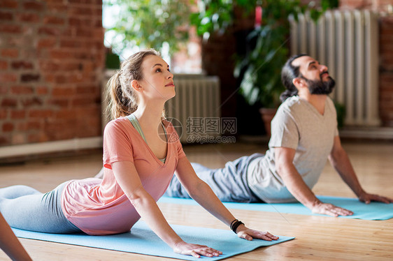 健身,人健康的生活方式男人女人瑜伽工作室的垫子上眼镜蛇姿势工作室瑜伽眼镜蛇姿势的男人女人工作室瑜图片