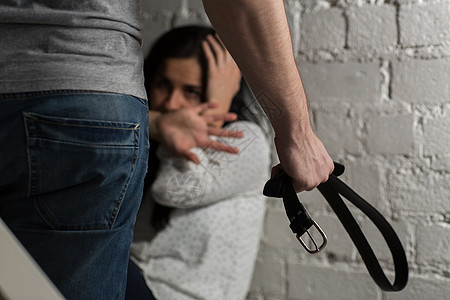 虐待人的男人用皮带殴打无助的害怕女人遭受的幸妇女图片