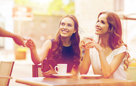 人,消费主义,生活方式友谊的微笑的轻妇女给服务员的手信用卡支付咖啡户外咖啡馆咖啡馆用信用卡支付咖啡的女人图片