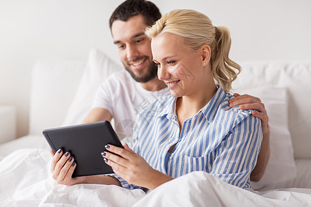 家庭,技术,互联网人的微笑幸福的夫妇与平板电脑电脑床上的家庭卧室微笑幸福的夫妇与平板电脑床上家图片