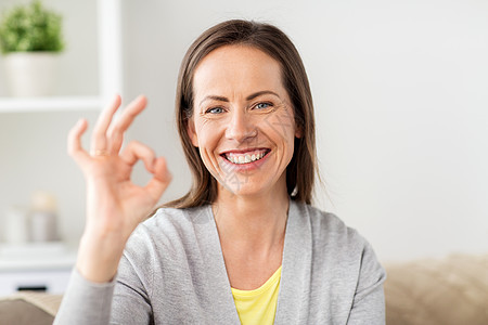 人手势快乐微笑的中妇女家里OK手势快乐的微笑的女人家里OK的手势图片