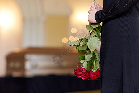 人们哀悼的教堂的葬礼上用红玫瑰棺材特写女人葬礼上用玫瑰棺材靠近女人图片