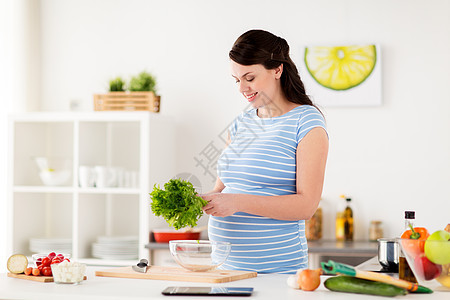 健康的饮食,怀孕人们的快乐的微笑孕妇与生菜烹饪蔬菜沙拉家里厨房孕妇家煮蔬菜沙拉图片