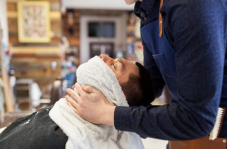 美容,剃须人的理发师软化男部皮肤与热毛巾理发店理发师用热毛巾软化男部图片