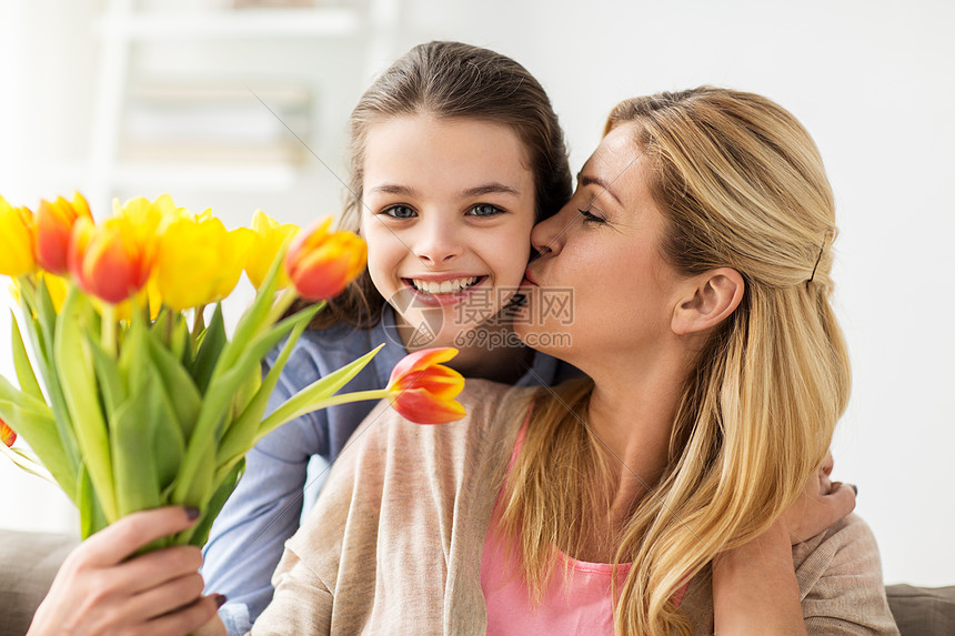 人,家庭假期的快乐的女孩送郁金香花亲吻她的母亲家里快乐的女孩家里给妈妈送花图片